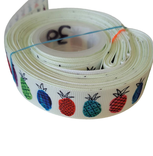 Roll of colorful ribbon with fruit patterns on a white background. Pineapples 