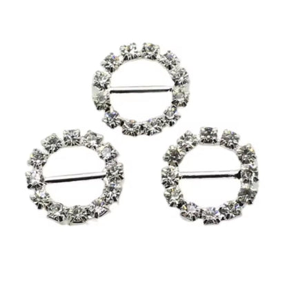 three circular brooches with rhinestone embellishments on a white background