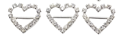 three heart-shaped brooches with diamond-like stones on a white background