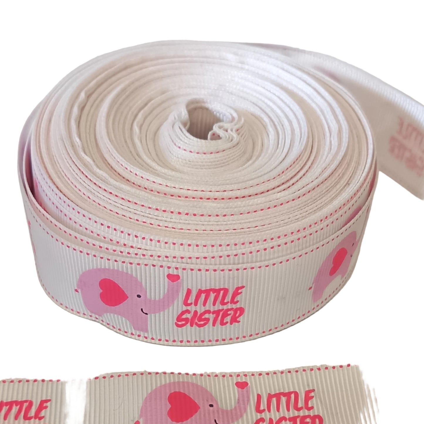 A roll of white grosgrain ribbon printed with pink elephants and the words 'LITTLE SISTER' in pink, shown on a light neutral background.