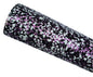 Black and white patterned fabric roll with pink specks on a white background