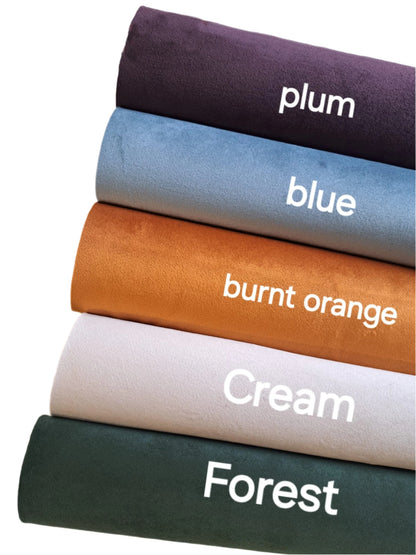 four rolls of coloured suede fabric on a white background